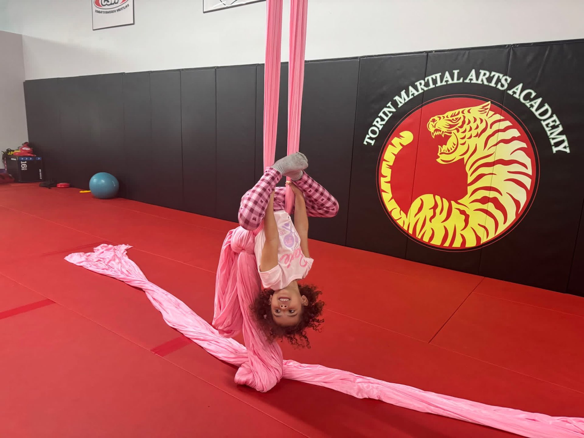 Student inverted in pink aerial silks
